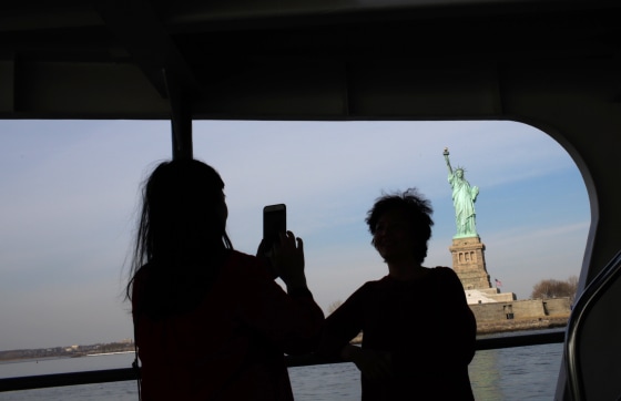 Image: Tourists take photos of the Statue of Liberty