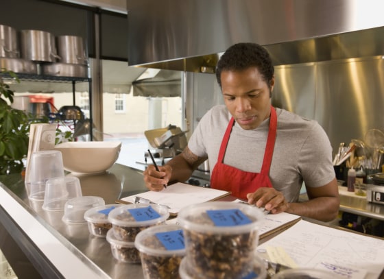 Image: A cook does paperwork in a commercial kitchen