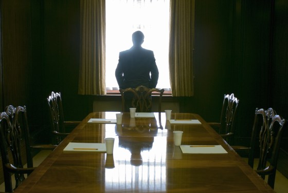 Image: A businessman looks out the window of a meeting room