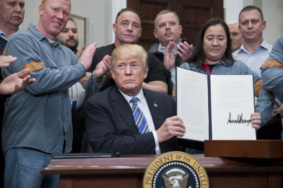 Image: President Donald Trump holds a presidential proclamation on steel tariffs