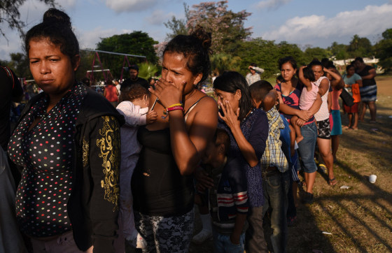 Image: Central American migrants taking part in a caravan called \"Migrant Via Crucis\" stand in line for food at a sports field