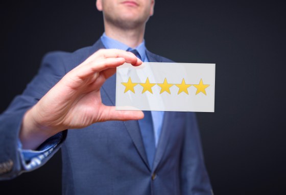 Businessman hand holding five stars isolated on black background. Business rating concept. Stock Photo
