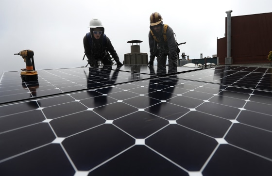 Image: Workers install solar panels on a roof