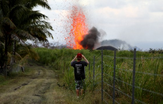 Image: A man takes a photo of a lava fountain from a Kilauea volcano fissure on Hawaii's Big Island on May 18, 2018 in Kapoho, Hawaii.