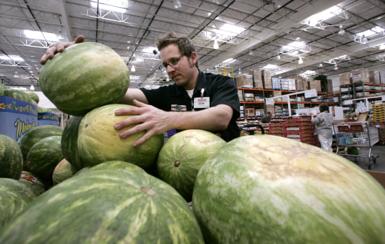 Image: A Costco produce stocker stacks watermelons on May 29, 2008.
