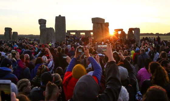 Image: Revelers watch the sunrise as they welcome the summer solstice