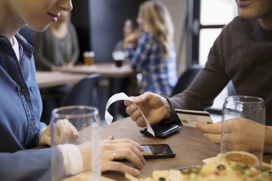 Image: A couple calculates the tip at a restaurant