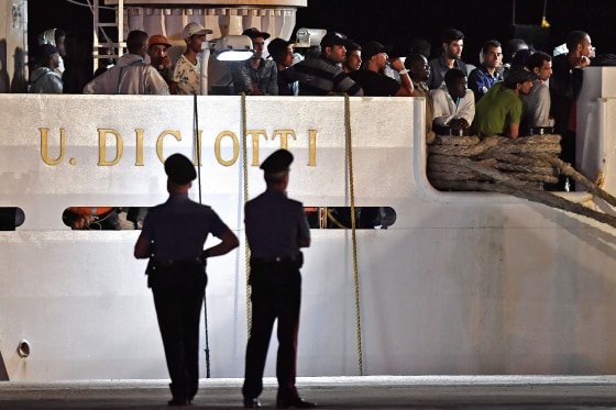Image: People wait to disembark from the Italian Coast Guard vessel \"Diciotti\" at the port of Pozzallo, Sicily