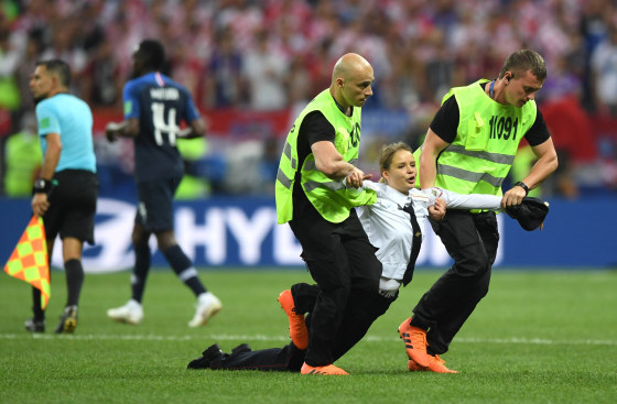 Image: A pitch invader is taken away by the security during the 2018 FIFA World Cup Final between France and Croatia