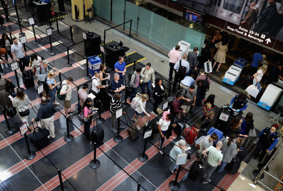 Image: Passengers stand in line outside a Transportation Security Administration checkpoint