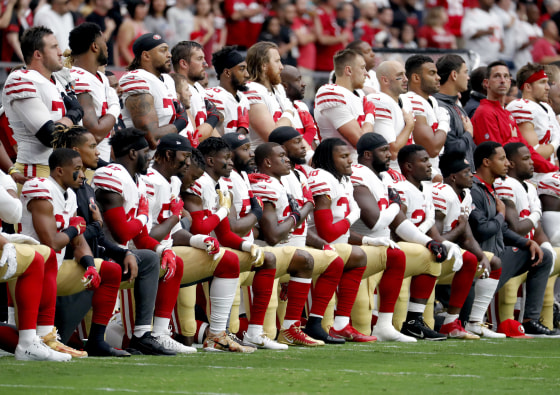 Image: Members of the San Francisco 49ers kneel during the national anthem