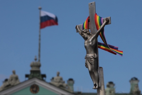 Image: A rainbow-colored ribbon tied to a crucifix is seen next to a Russian flag