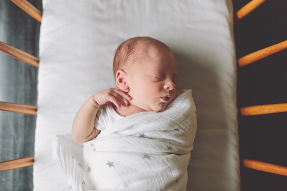 Image: Newborn baby boy swaddled in cot, overhead view
