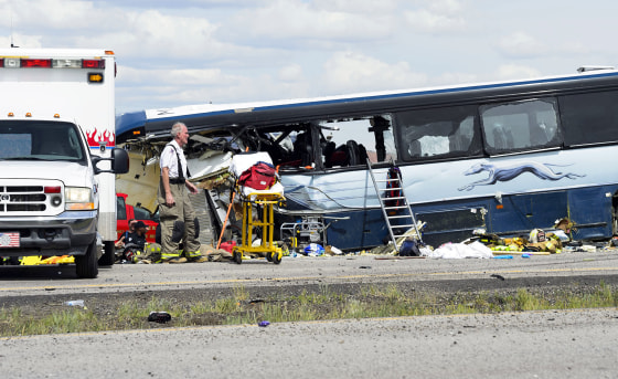 Image: A firefighter looks at the scene of the collision of a semitrailer that crossed the median of Interstate 40 and crashed head-on into a Greyhound bus