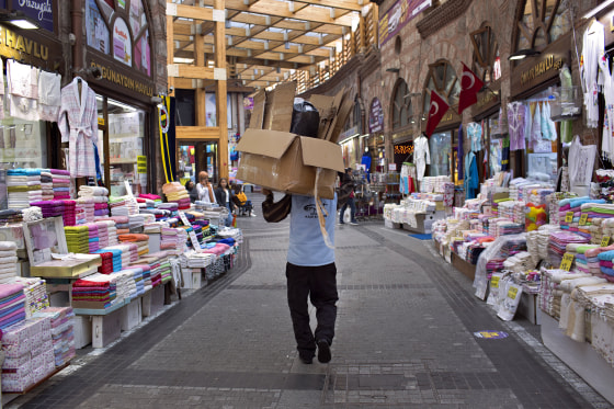 Image: A man carries empty cardboard boxes through a market in Bursa, Turkey.