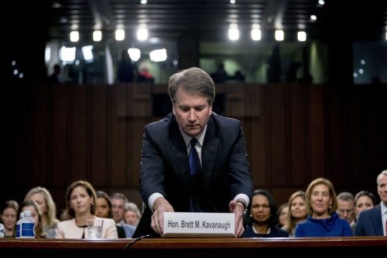Image: Brett Kavanaugh fixes his name sign after being sworn in as he appears before the Senate Judiciary Committee