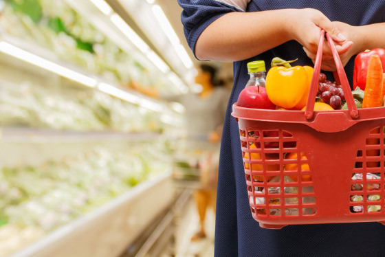 a woman holds a basket filled with groceries