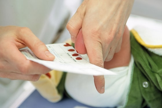 A midwife takes a blood sample from a newborn