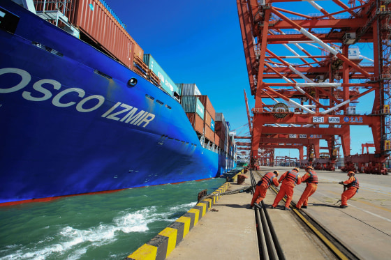 Image: Workers pull a line from a cargo ship as it prepares to berth at a port in Qingdao in China's eastern Shandong province