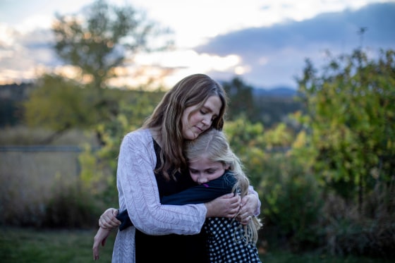 Kristen Kilmer hugs her 12-year-old daughter at their home in Spearfish, South Dakota.