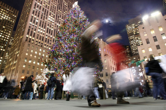 Shoppers walk past the Rockefeller Center Christmas tree in New York.