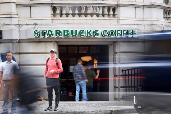 Patrons enter a Center City Starbucks, while a car blurs past, before more than 8,000 store nationwide will close this afternoon for anti-bias training, in Philadelphia, Pennsylvania