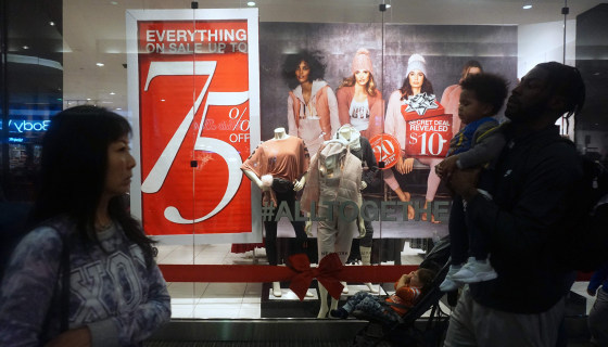 Image: Shoppers walk past sale signs for Black Friday at a mall in Montebello