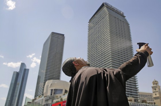 Image: Chris Mitchell sprays water on his face to cool off