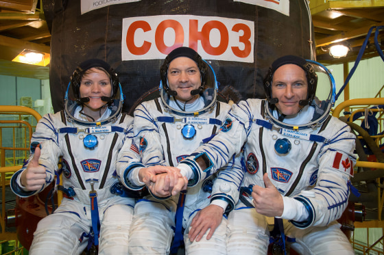 NASA astronaut Anne McClain (left), Russian cosmonaut Oleg Kononenko (center) and David Saint-Jacques of the Canadian Space Agency (right) pose in front of their Soyuz MS-11 spacecraft.