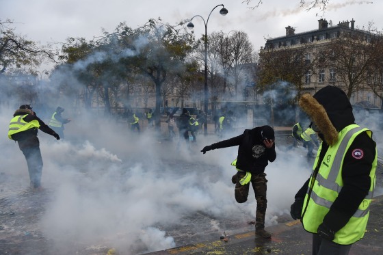 Image: Demonstrators try to avoid riot police smoke grenades
