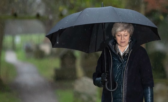 Image: Britain's Prime Minister Theresa May shelters from the rain under an umbrella after attending a church service near to her Maidenhead constituency