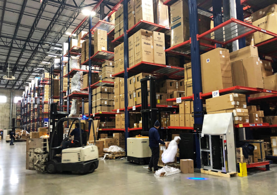 Image: Warehouse workers deal with inventory stacked up to the ceiling at an ABT Electronics Facility in Glenview