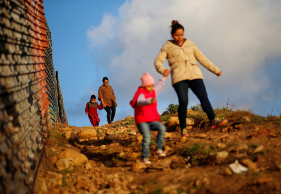 Image: Migrants from Honduras, part of a caravan of thousands from Central America trying to reach the United States, walk next to the border fence as they prepare to cross it illegally, in Tijuana,