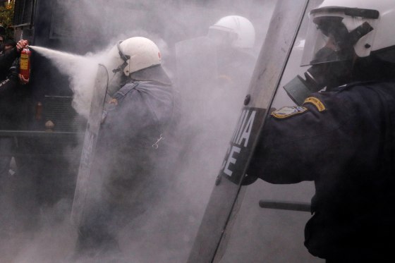 Image: A protester uses a fire extinguisher against riot police during clashes outside the parliament building as Greek school teachers demonstrate against government plans to change hiring procedures in the public sector in Athens