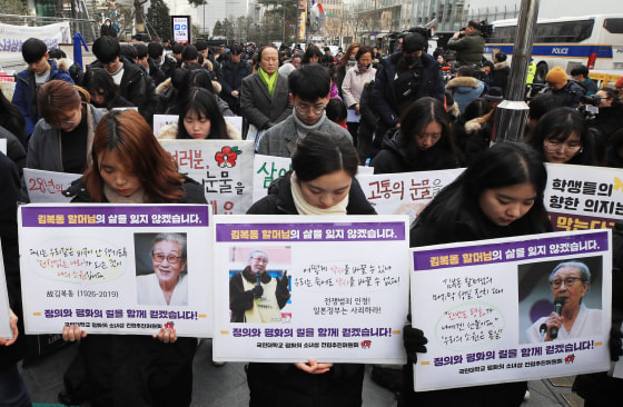 Mourners hold pictures of Kim Bok-dong during a moment of silence at a weekly rally near the Japanese Embassy in Seoul, on Jan. 30, 2019.