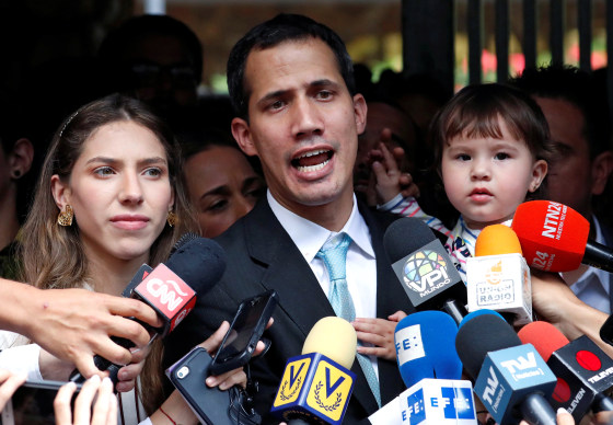 Image: Venezuelan opposition leader and self-proclaimed interim president Juan Guaido talks to media next to his wife Fabiana Rosales, while carrying their daughter outside their home in Caracas