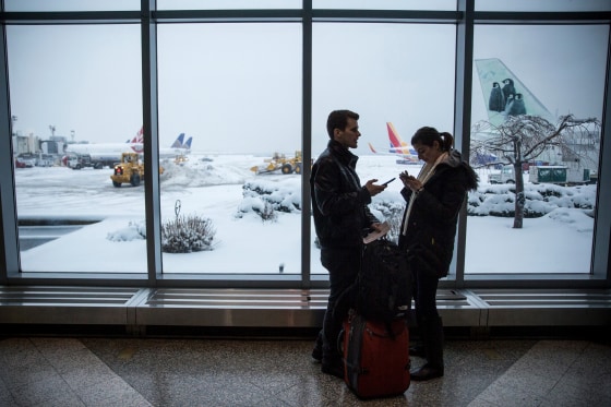 Image: Travelers check their phones while waiting for a flight at LaGuardia Airport during a winter storm in Queens, New York, on Feb. 2, 2015.