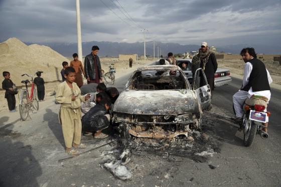 Image: A group of Afghan civilians look at a burnt vehicle near the Bagram Air Base near Kabul after a roadside bomb detonated, killing three American service members, in Afghanistan on April 9, 2019.