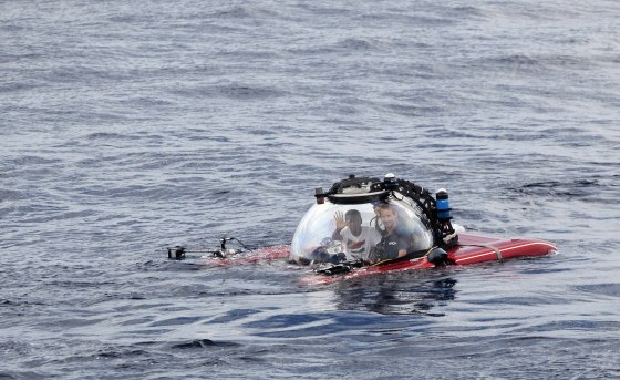 Image: Seychelles President Danny Faure waves as he emerges from the ocean inside a submersible off the coast of the Seychelles on April 14, 2019.