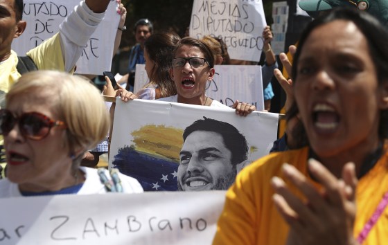 Image: A woman holds an image of jailed opposition lawmaker and outspoken critic of President Nicolas Maduro