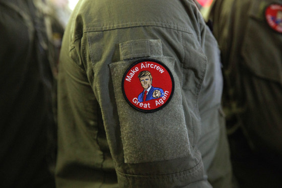 Image: A service member wears a patch that says \"Make Aircrew Great Again\" as they listen to President Donald Trump speak to troops at a Memorial Day event aboard the USS Wasp