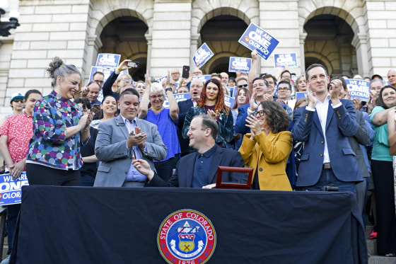 Gov. Jared Polis is applauded upon signing two LGBTQ bills on May 31, 2019.