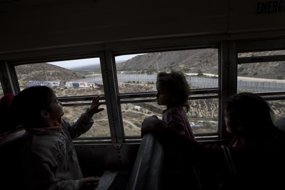 Image: Central American children who are traveling with a caravan of migrants look at the border wal