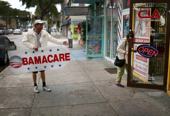 Image: Pedro Rojas holds a sign directing people to an insurance company where they can sign up for the Affordable Care Act, also known as Obamacare in Miami, Florida.