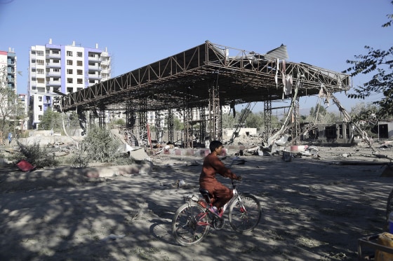 Image: An Afghan boy rides a bicycle through the aftermath of an attack in Kabul, Afghanistan