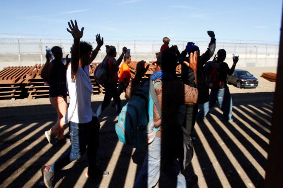 A group of migrants hold up their hands as border patrol officers detain them in Tijuana, Mexico, on Nov. 25, 2018.