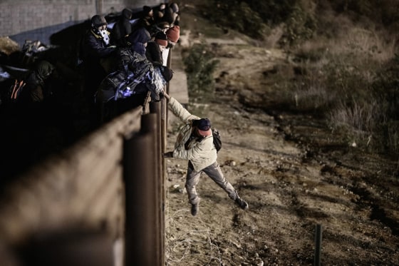 Image: A migrant jumps the border fence to get into the U.S. side to San Diego, Calif., from Tijuana, Mexico