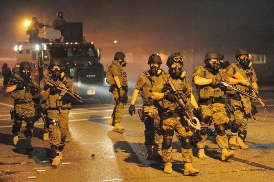 Law enforcement officers watch on during a protest on West Florissant Avenue in Ferguson, Missouri on August 18, 2014. Police fired tear gas in another night of unrest in a Missouri town where a white police officer shot and killed an unarmed black teenager, just hours after President Barack Obama called for calm.