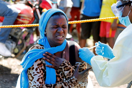 Image: A young woman reacts as a health worker injects her with the Ebola vaccine, in Goma