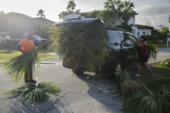 Victoria Casanova and Arryngton Turner stuff palm fronds into the back of their Midsize SUV. The couple, once local residents, drove down from Georgia as part of their tree trimming business to cut back palm fronds, which many worry will become projectiles that can cause damage to buildings and people during Hurricane Dorian.